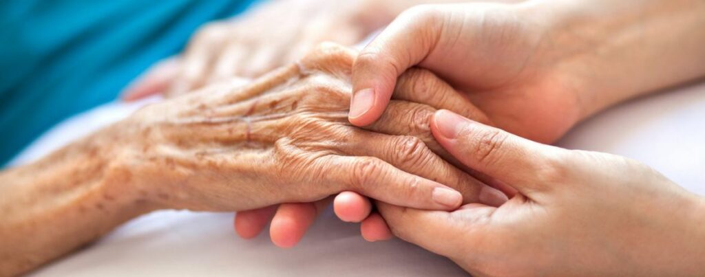 image of elderly hand being held by younger hands | Palliative care