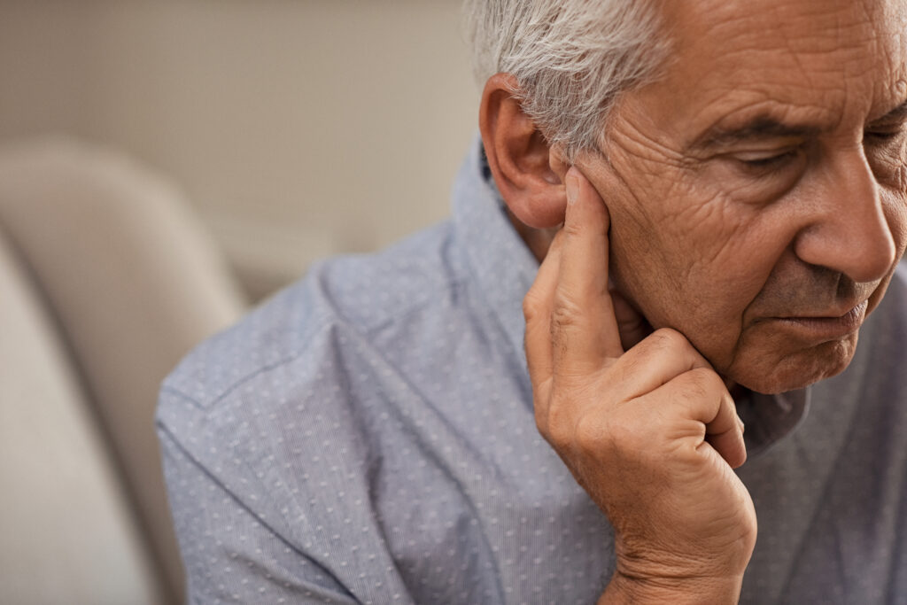 hearing loss and dementia  |elderly man holding fingers to ear 