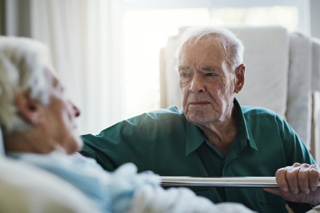 Palliative care | Senior man looking at his wife who lies in a hospital bed