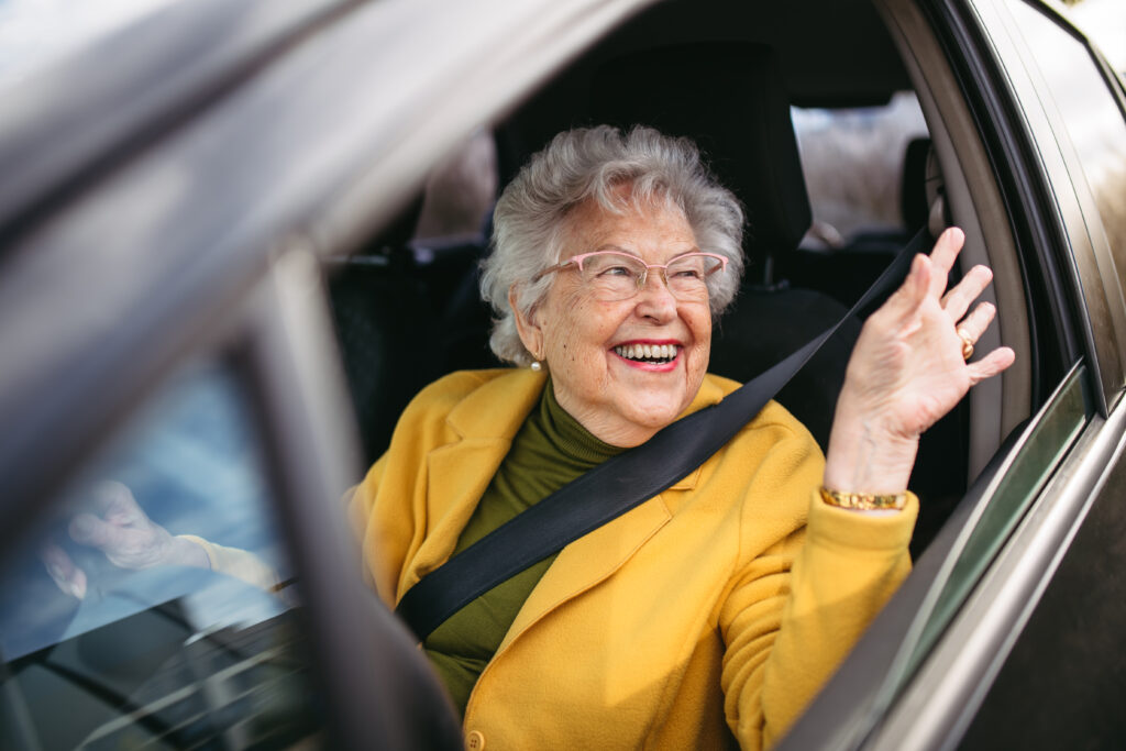 A senior enjoying a laugh with family during a car ride, highlighting the joy of togetherness beyond the need to drive. after relinquishing a driving license "The warmth of family togetherness, showing that the journey is about more than just driving—it's about shared moments and care."